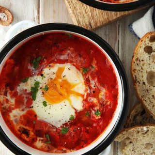 A dish of shakshuka on a white table with bread