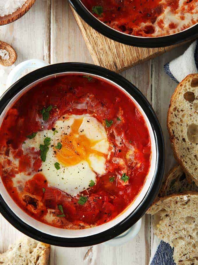 A dish of shakshuka on a white table with bread