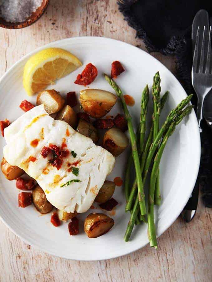 A close up picture of Cod & Chorizo with new potatoes and asparagus