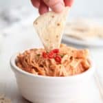 A chip being dipped into a bowl of buffalo chicken dip
