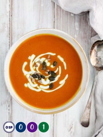 A bowl of orange soup on a white table