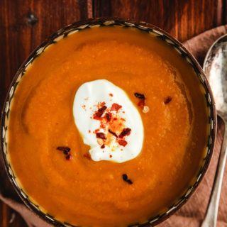 A bowl of curried pumpkin soup on a wooden table