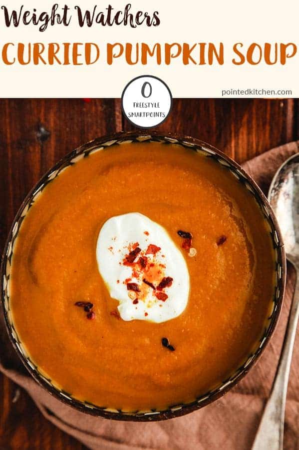 A bowl of curried pumpkin soup on a wooden table.