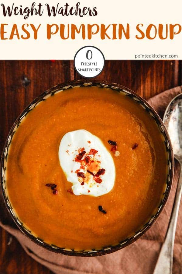 A bowl of curried pumpkin soup on a wooden table.