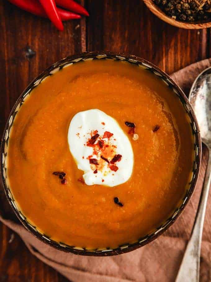 A bowl of curried pumpkin soup on a wooden table