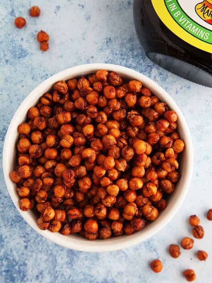 A white bowl full of marmite chickpeas with some on the table
