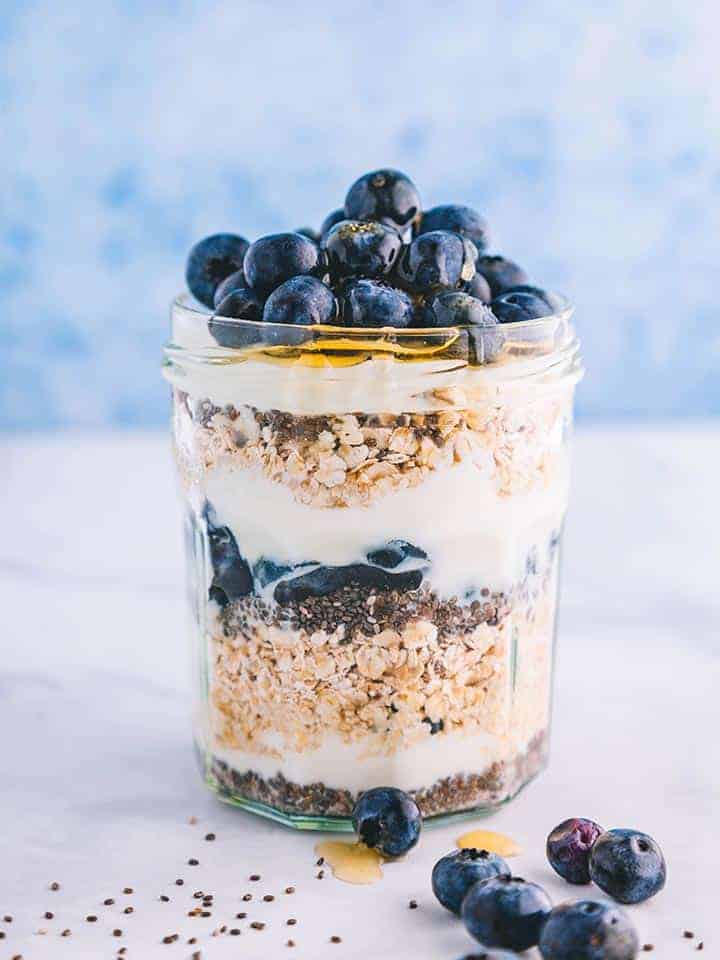 A jar layered with oats, chia seeds, blueberries and yogurt.