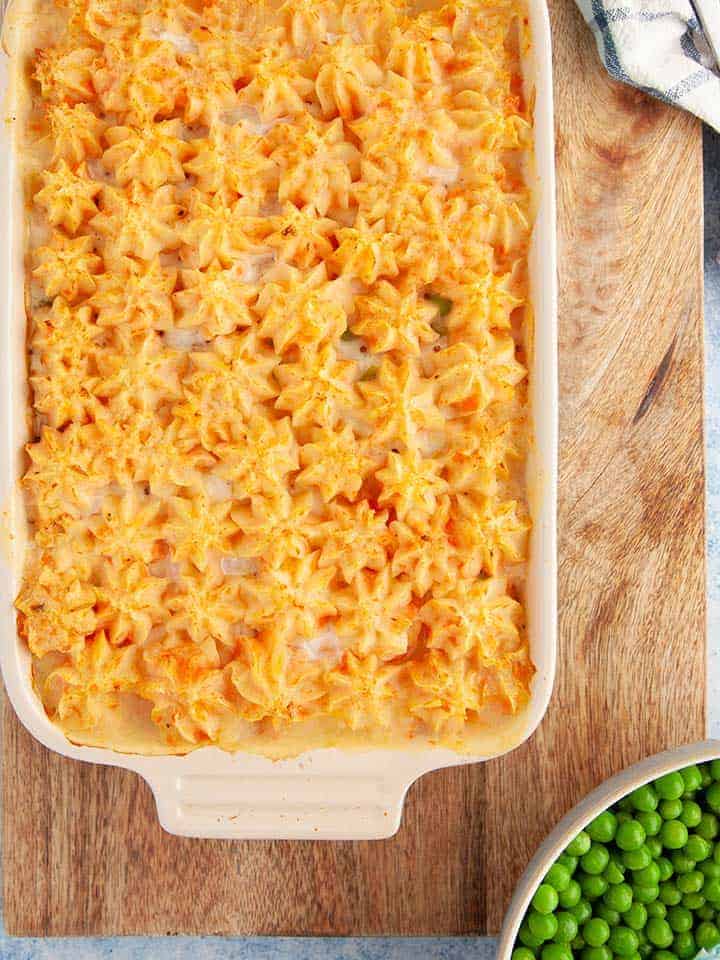 A casserole dish of fish pie on a wooden board