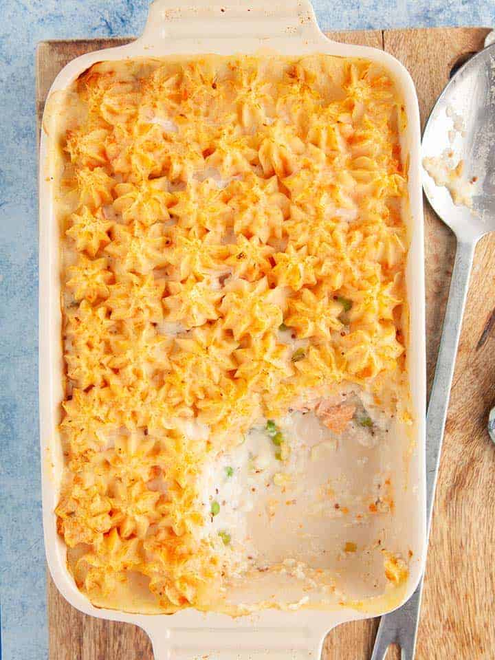 A fish pie on a wooden board with a spoon