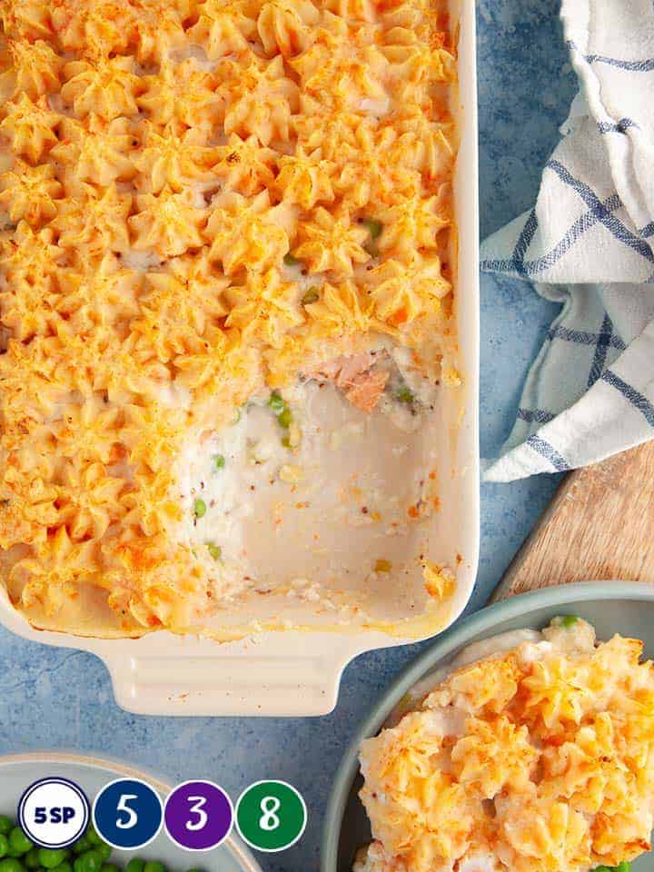 A casserole dish of fish pie on a blue table