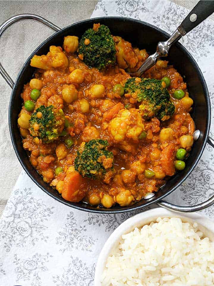 A dish of curry next to a bowl of white rice