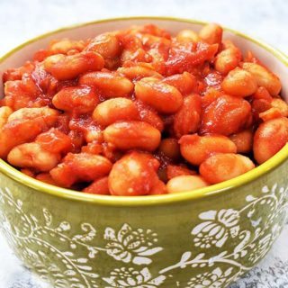 A green bowl full of red baked beans