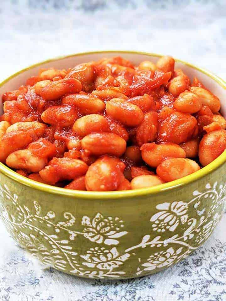A green bowl full of red baked beans