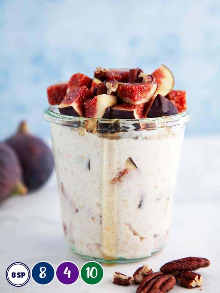 A glass pot full of overnight oats with some figs and honey