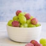 A bowl of grapes that are covered in jello crystals