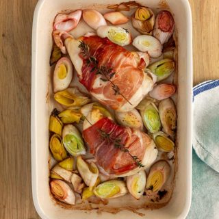 A dish of chicken and leeks on a wooden table