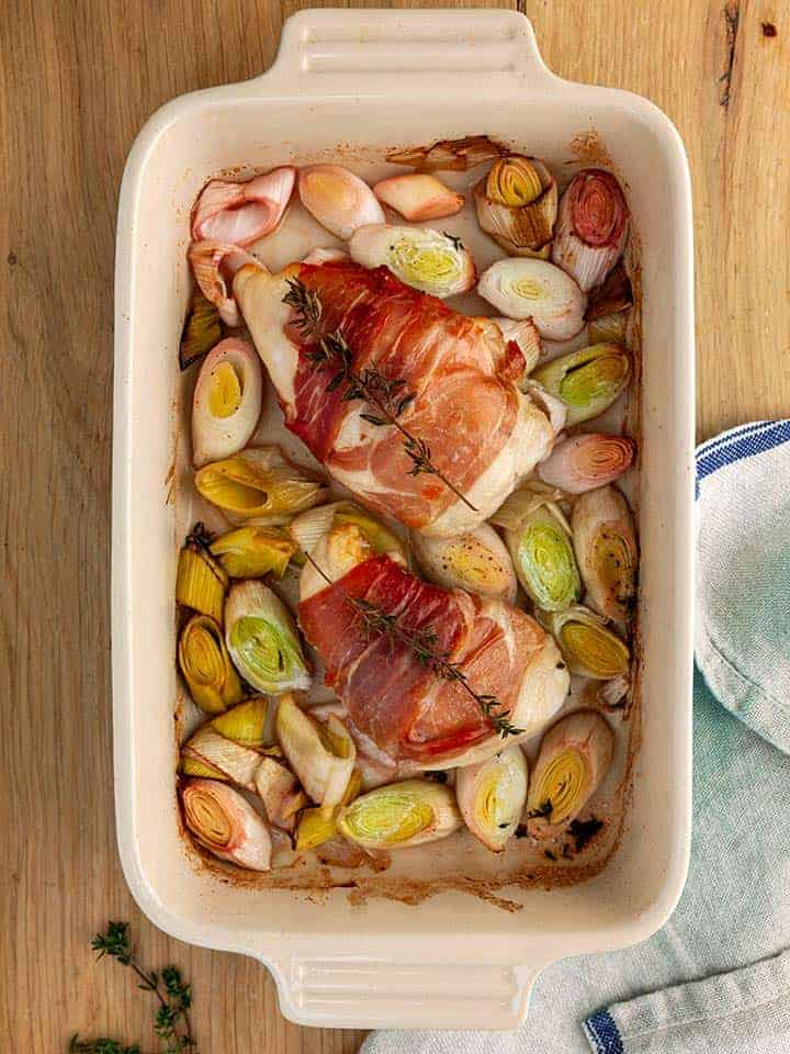 A dish of chicken and leeks on a wooden table