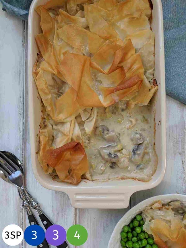 A dish of chicken leek & mushroom pie on a wooden table