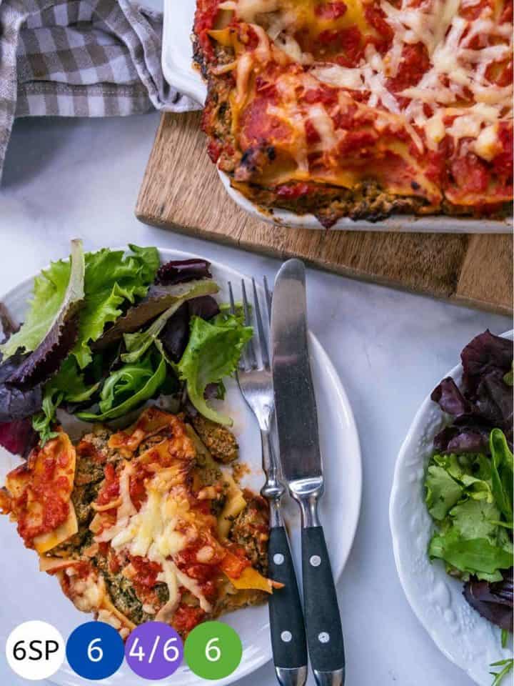 A white plate with some vegetable lasagna and salad