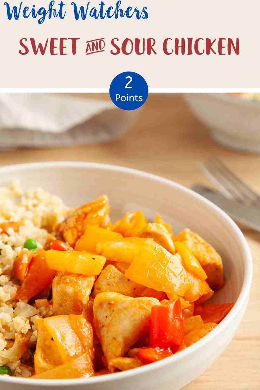 A white bowl of sweet & sour chicken with cauliflower rice on a wooden table