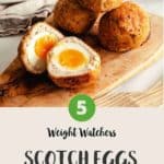 Four scotch eggs on a wooden board with one egg cut in half