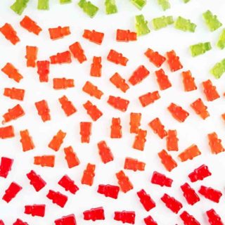Red, green and orange gummy bears on a white table