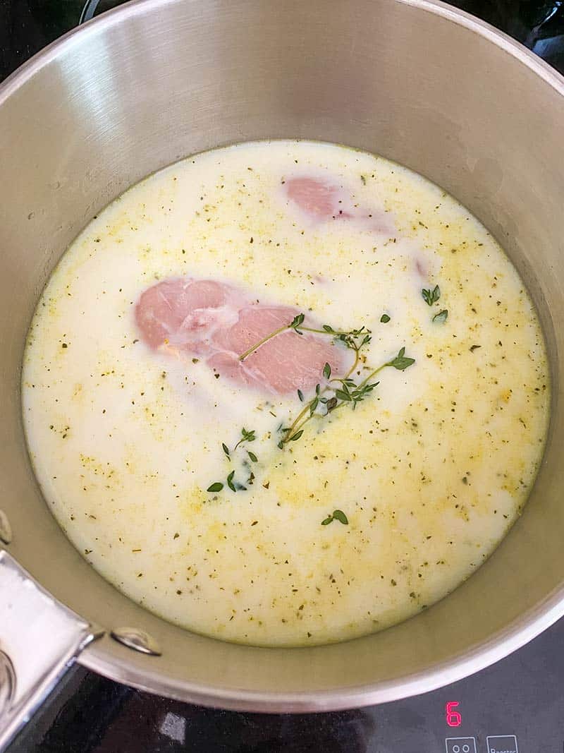 Chicken breasts poaching in milk with fresh thyme