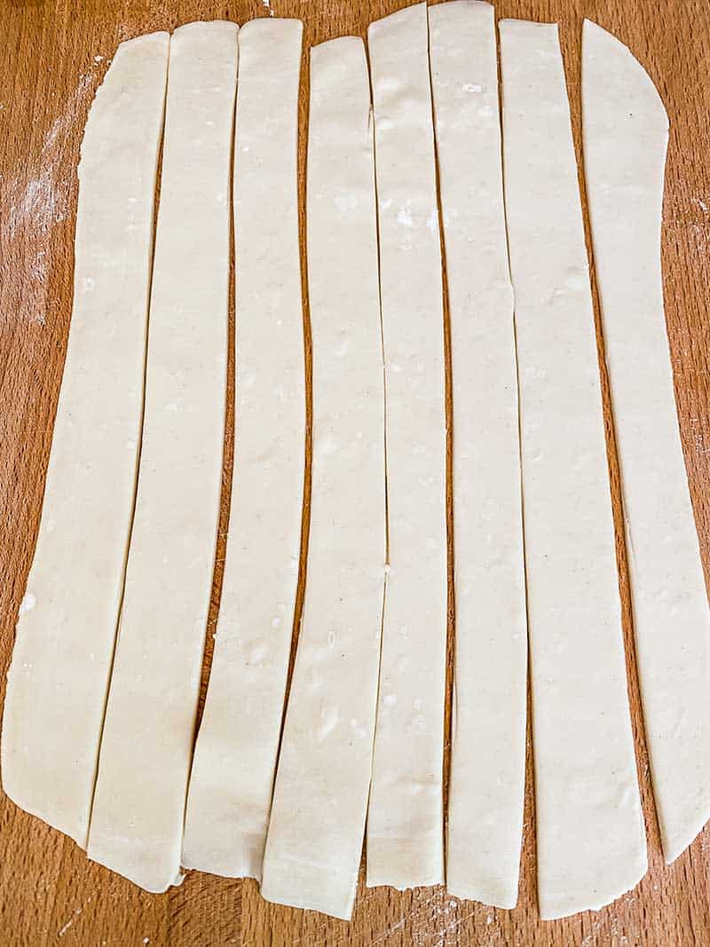 Puff pastry cut into 8 strips on a wooden board