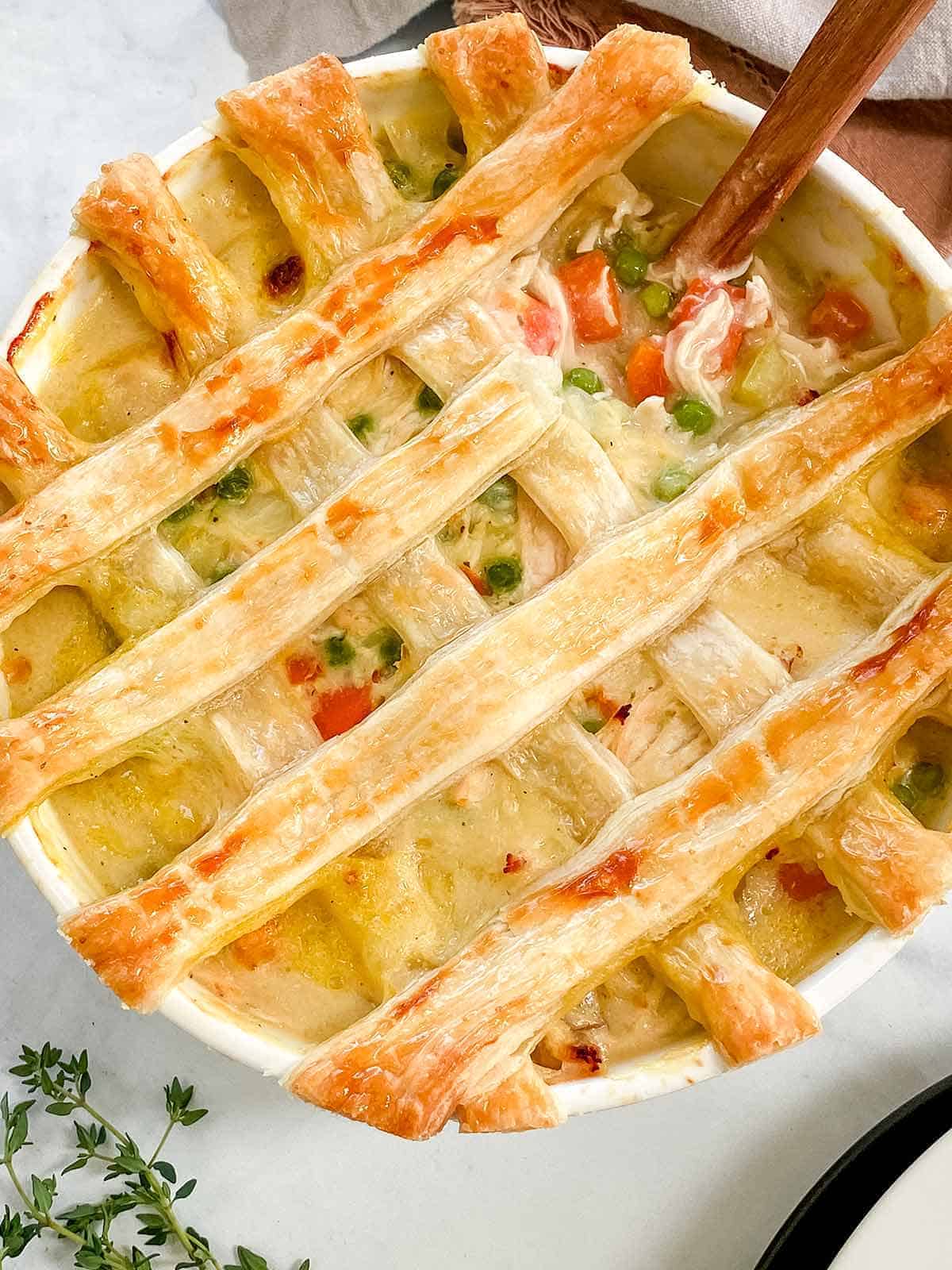 A close up picture of a latticed Chicken Pot Pie with a wooden spoon