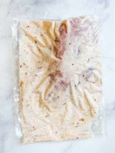 A plastic bag with chicken marinating in a yogurt sauce