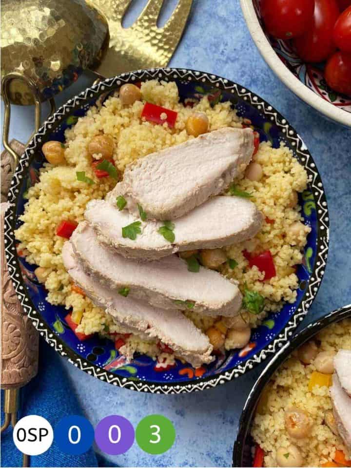 A dish of couscous salad with sliced chicken