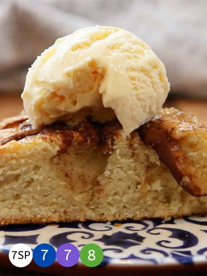 A close up of apple cake with a dollop of vanilla ice cream on top.