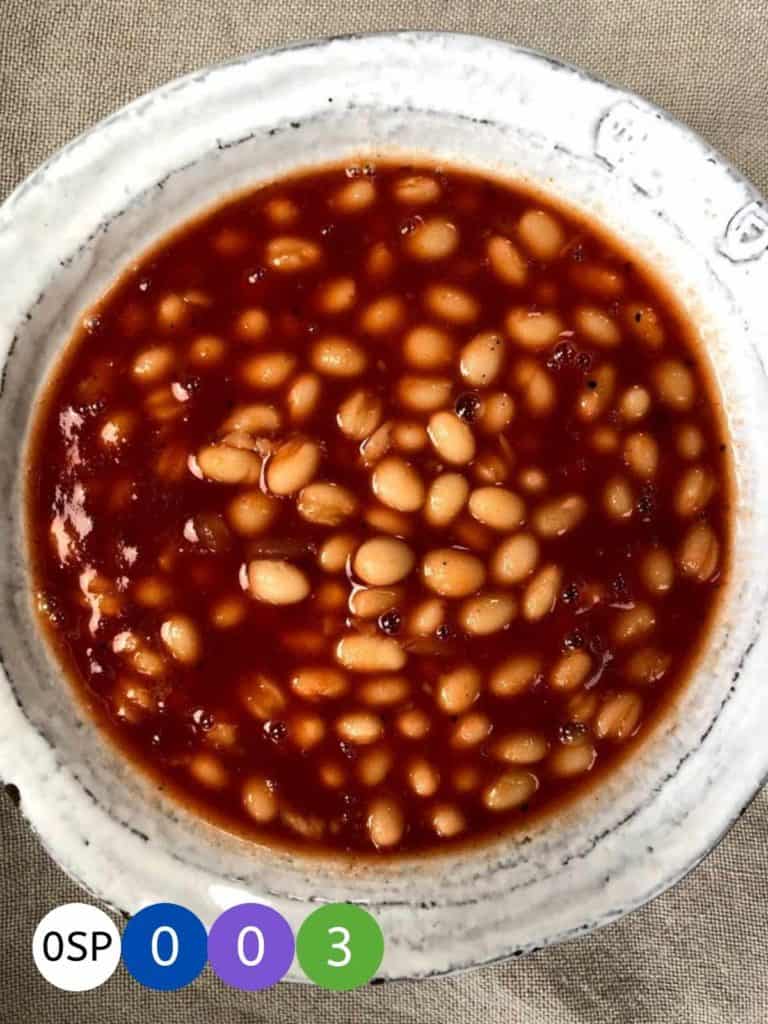 A white ceramic bowl full of bbq baked beans.