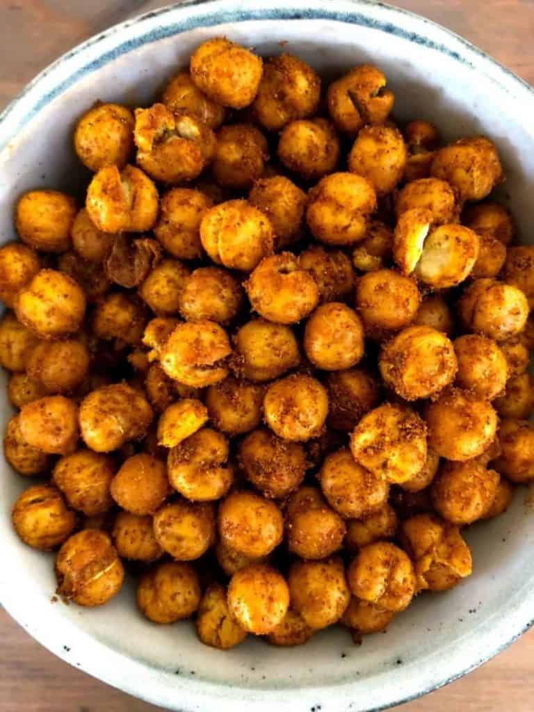 A bowl of shawarma coated chickpeas on a wooden table.