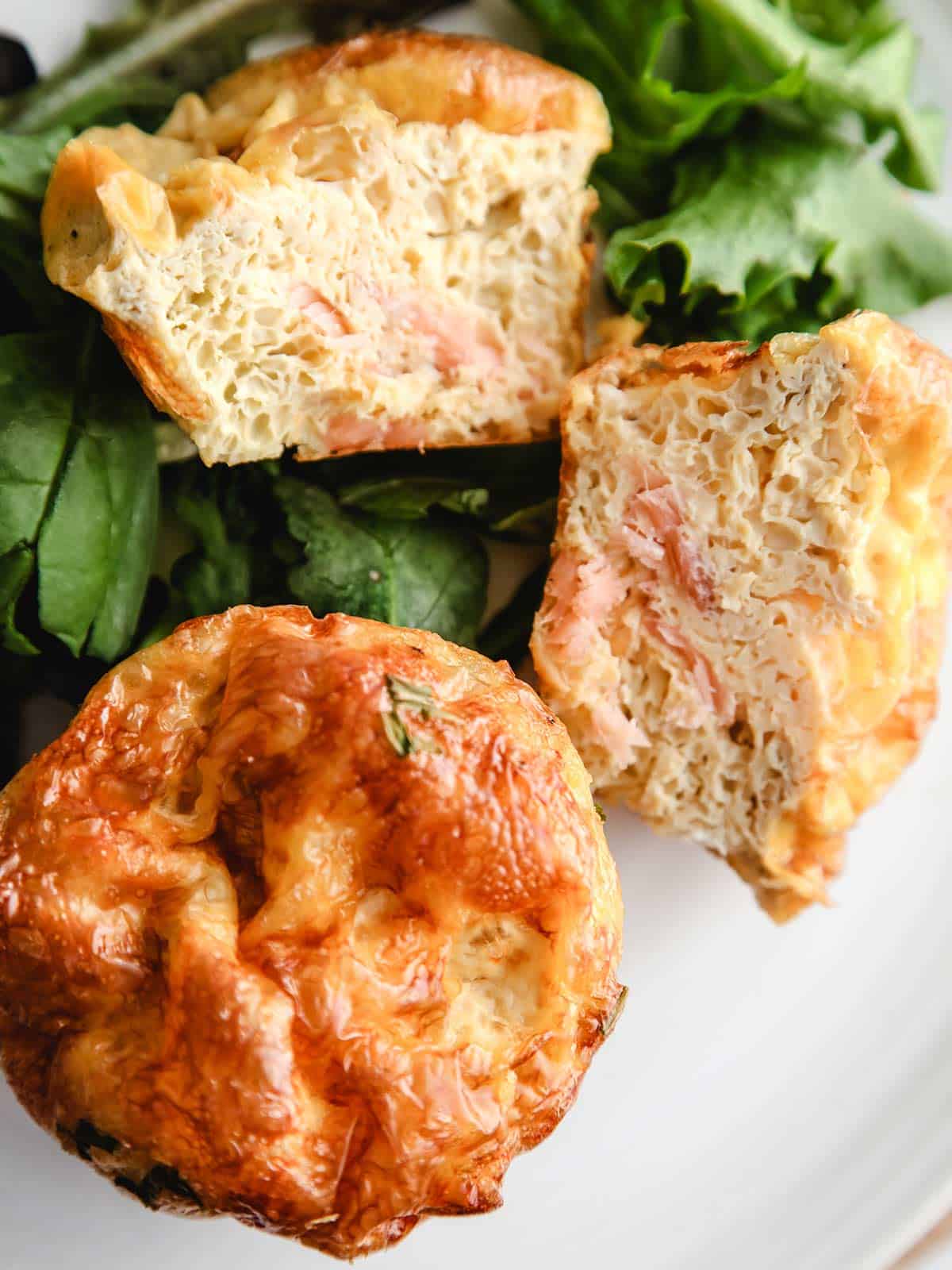 Two smoked salmon breakfast muffins on a bed of green lettuce.