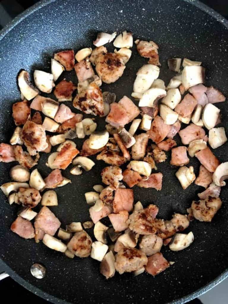 A skillet of chopped bacon, mushroom and sausage.