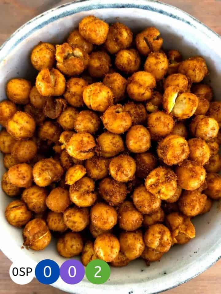 A bowl of shawarma coated chickpeas on a wooden table.