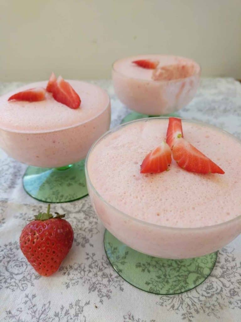 Three dishes of pink strawberry fluff with sliced strawberries on top.