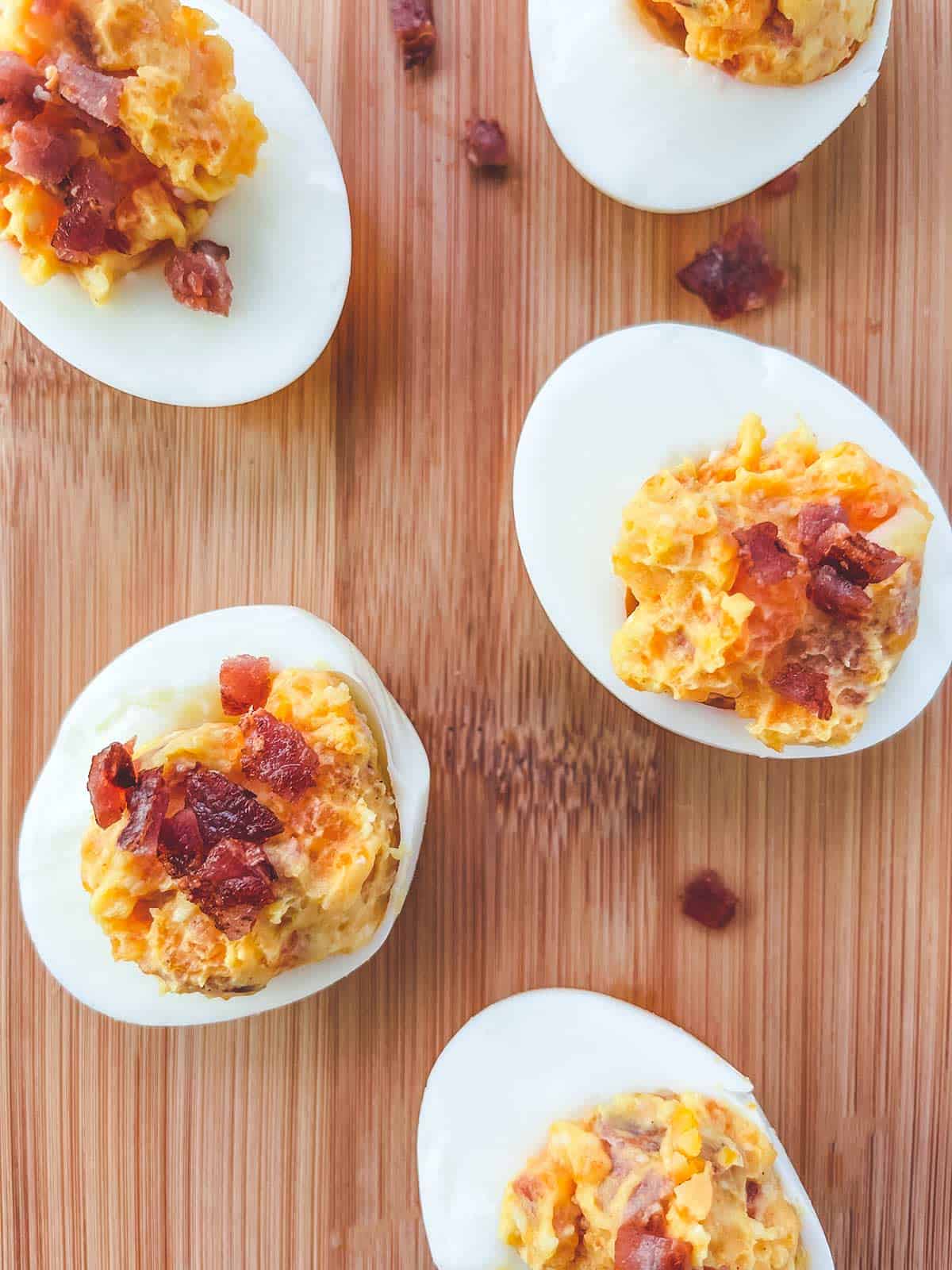 5 cheese and bacon stuffed eggs on a wooden board.