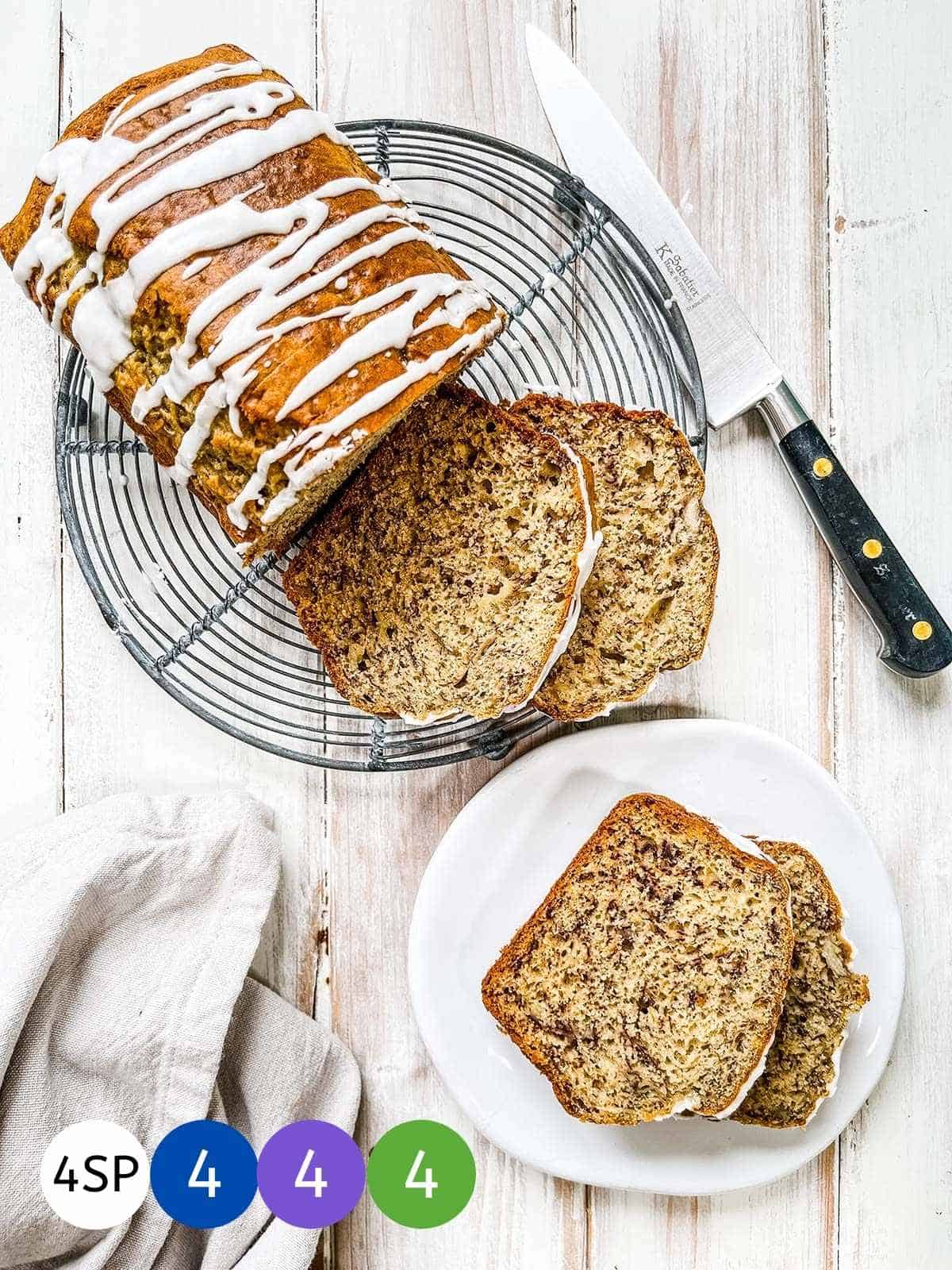 A banana bread loaf on a white table with SmartPoint values in colored circles.