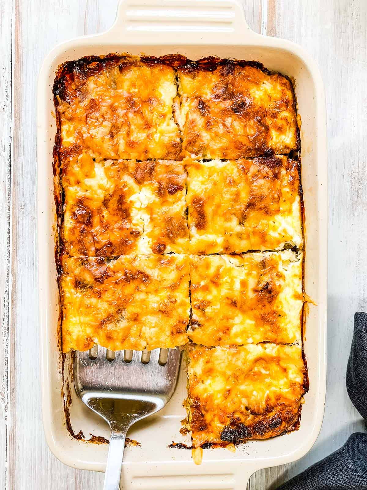 The baked casserole cut into 8 slices with one piece missing.