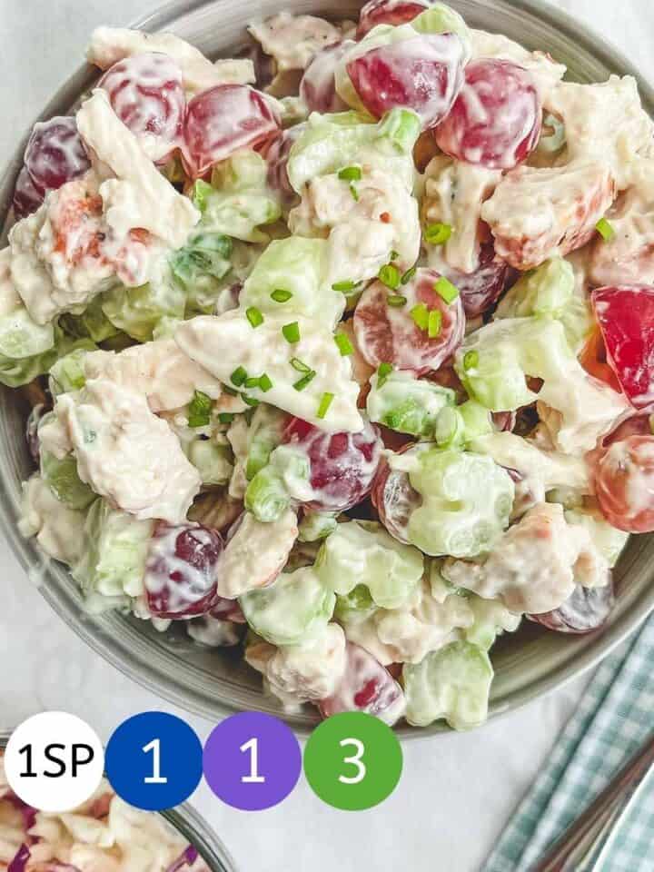 A bowl of chicken, grape and celery salad on a white table with coloured circles showing WW smartPoint values.