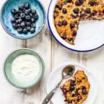 A white table with a dish of baked oatmeal and blueberries.