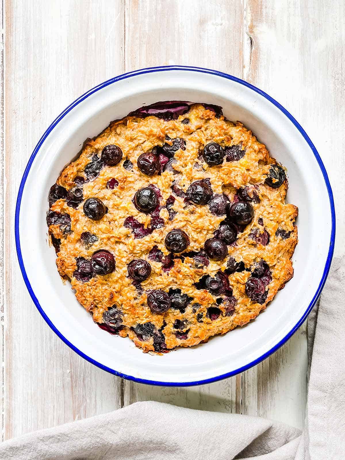 A white dish of baked oatmeal on a white table.