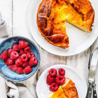 A yogurt tart on a white table with a bowl of raspberries.