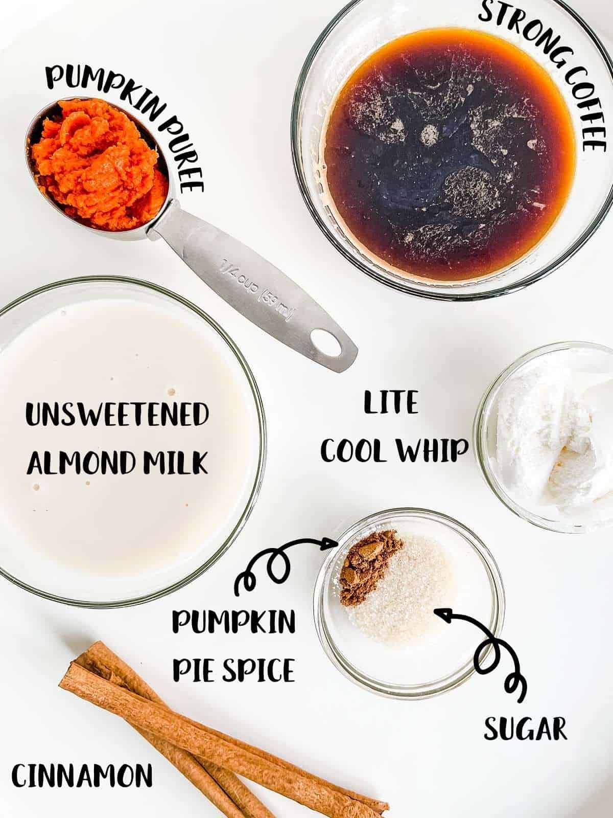 Ingredients laid out on a white table to make pumpkin spice latte.