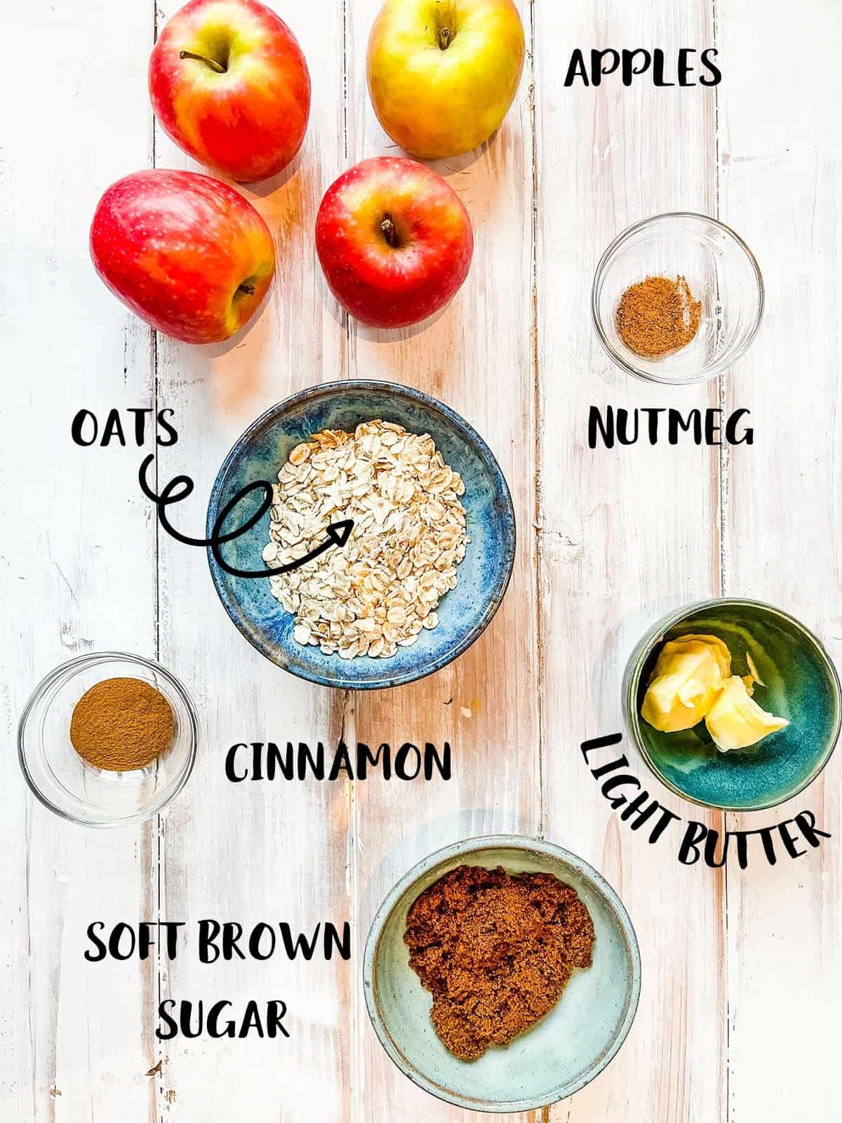 The ingredients needed to make baked apples laid out on a wooden table.