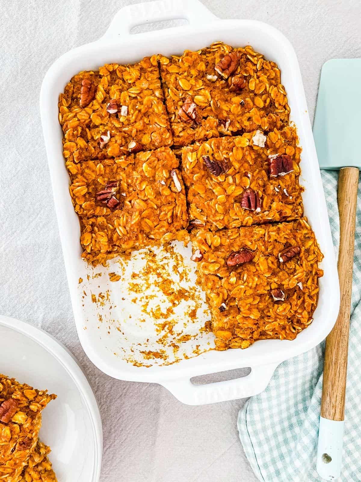 A white ceramic dish full of baked oats on a linen tablecloth.