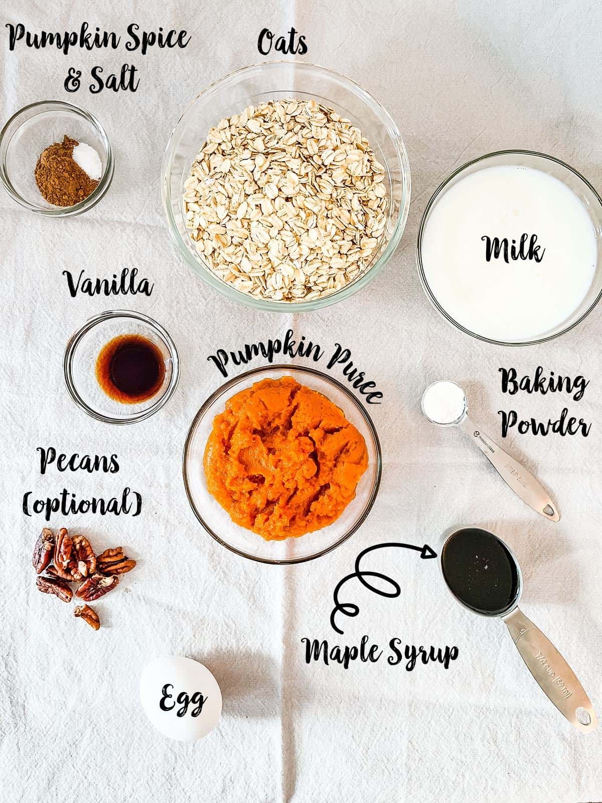 Ingredients for pumpkin baked oatmeal laid out on a table - all labeled.