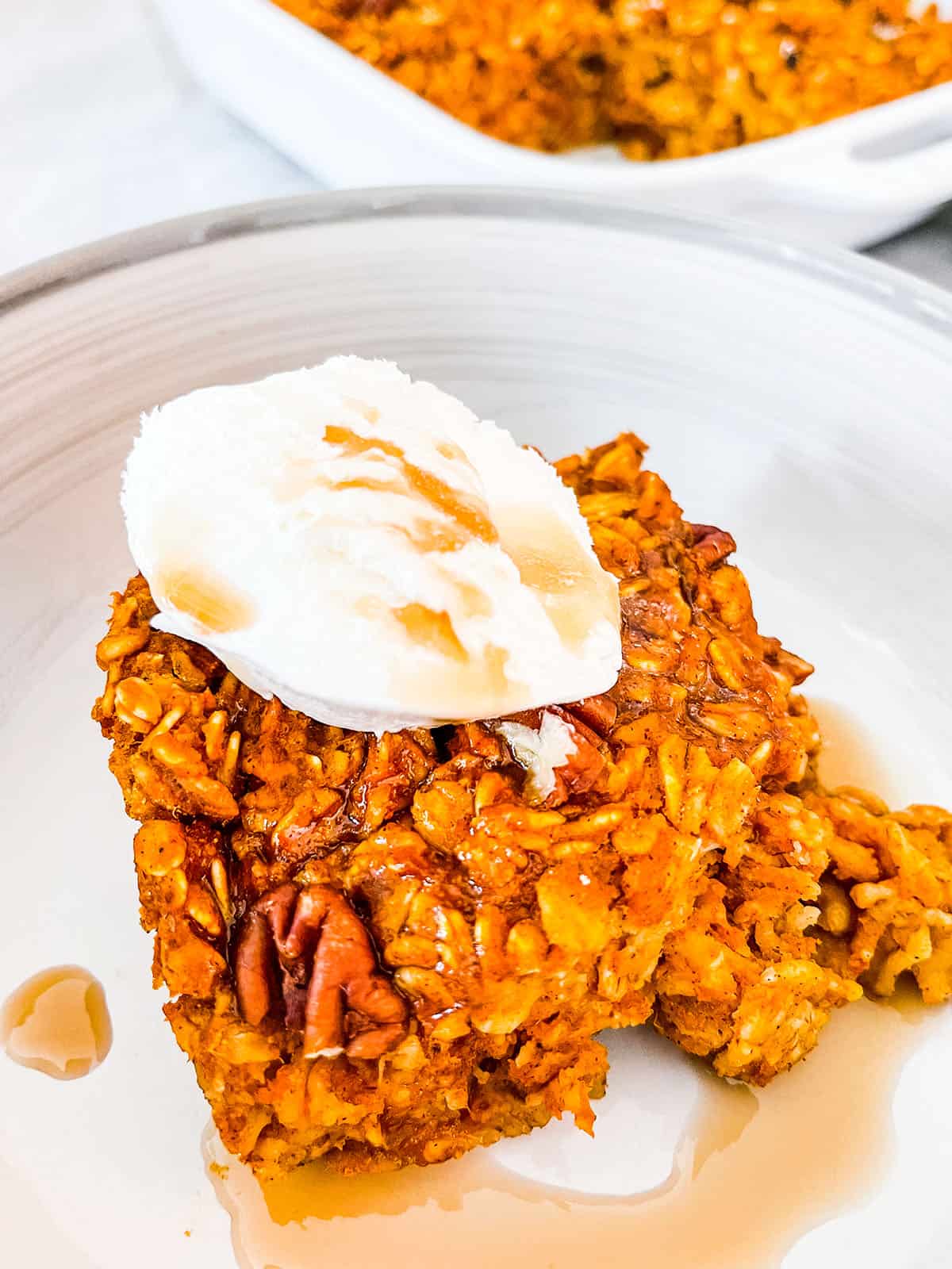 A close up picture of pumpkin baked oatmeal topped with coolwhip and maple syrup.